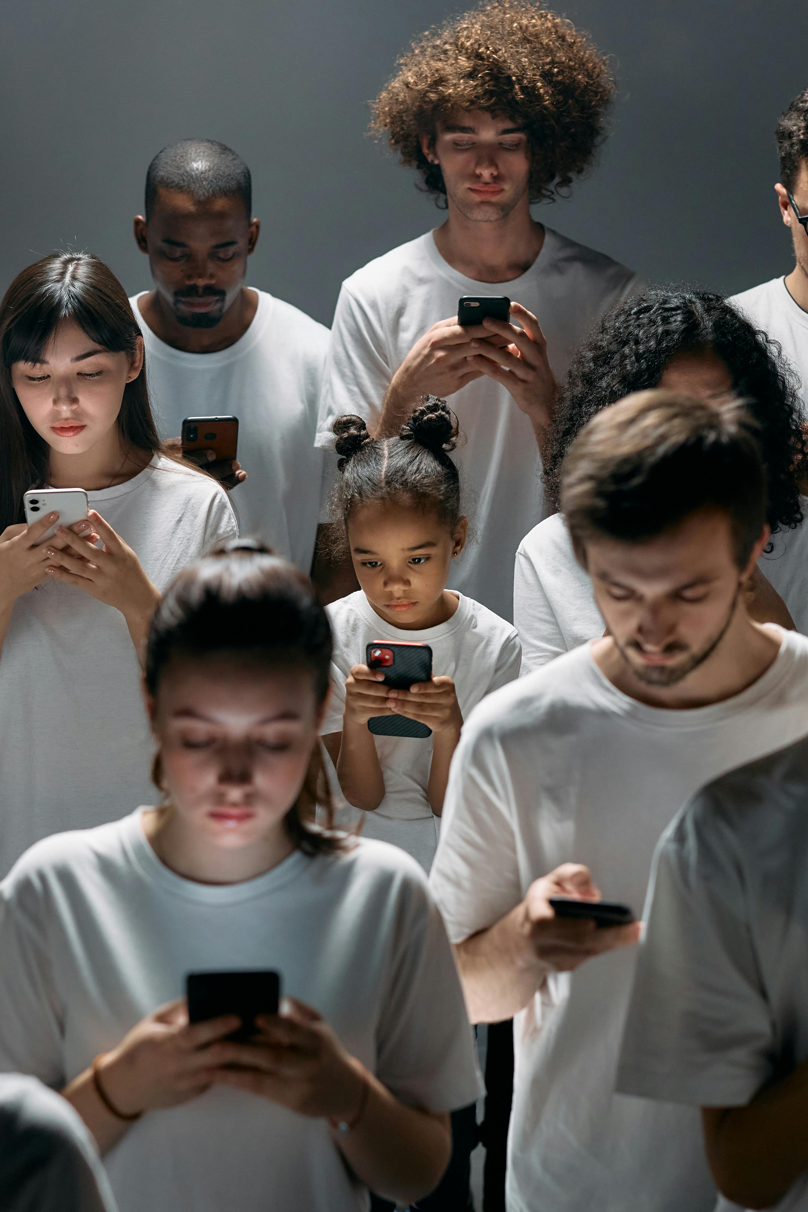 A group of diverse people staring at their phones in their hands.