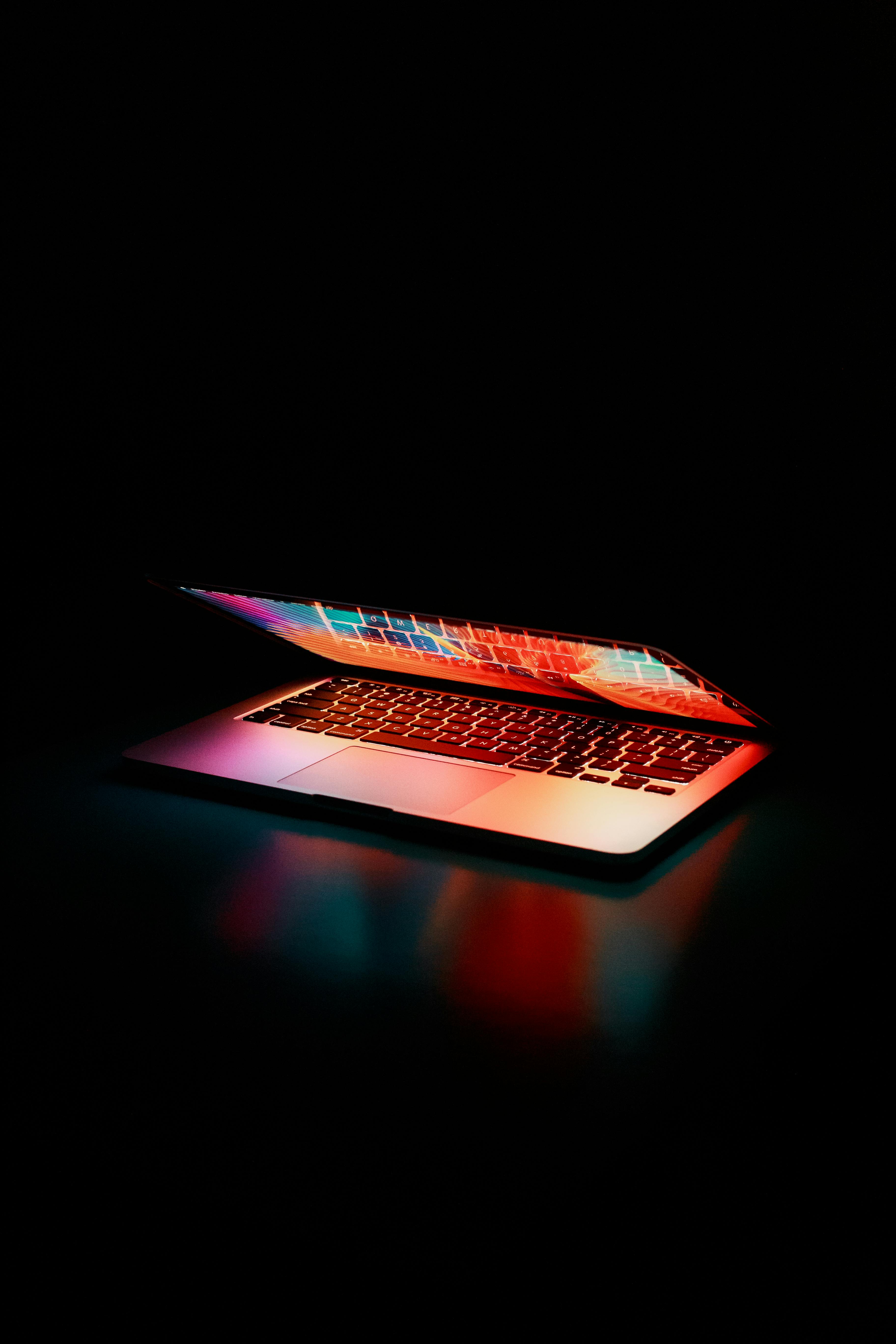 dark themed image with a slightly opened laptop illuminating.